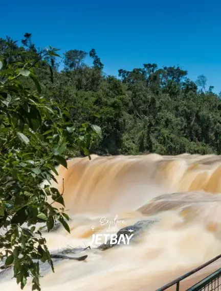 Powerful waterfall cascades over rocks surrounded by lush tropical vegetation in Ciudad Del Este, Paraguay