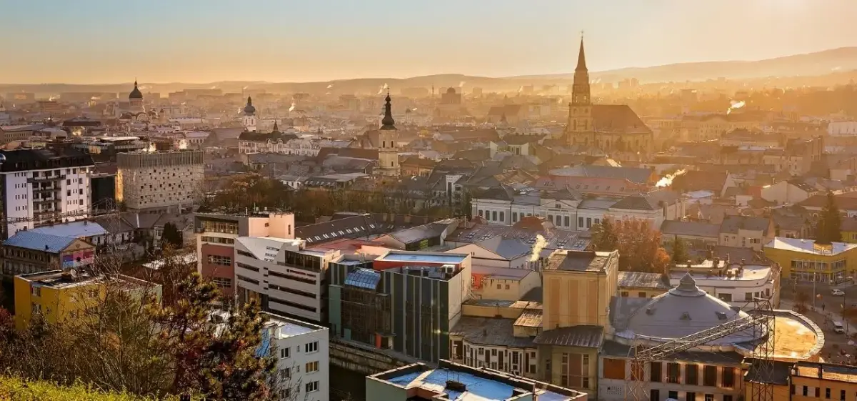 Golden sunset illuminating Cluj-Napoca's historic skyline with Gothic cathedral spire and traditional Romanian architecture
