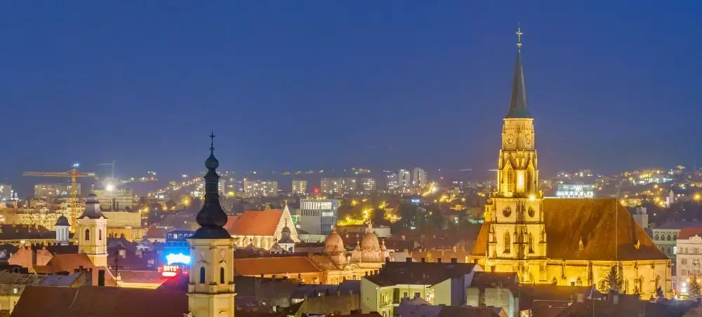 Cluj-Napoca's illuminated historic center at twilight showcasing Gothic spires and medieval architecture