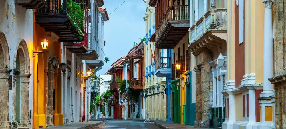 Colorful colonial buildings with wooden balconies line cobblestone street in historic Cartagena, Colombia