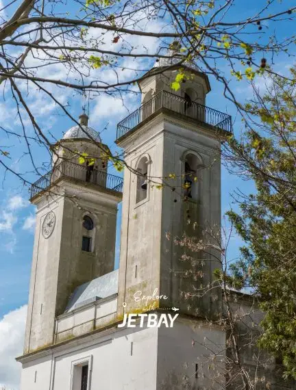 Historic twin bell towers of Colonia del Sacramento cathedral framed by spring branches under blue sky