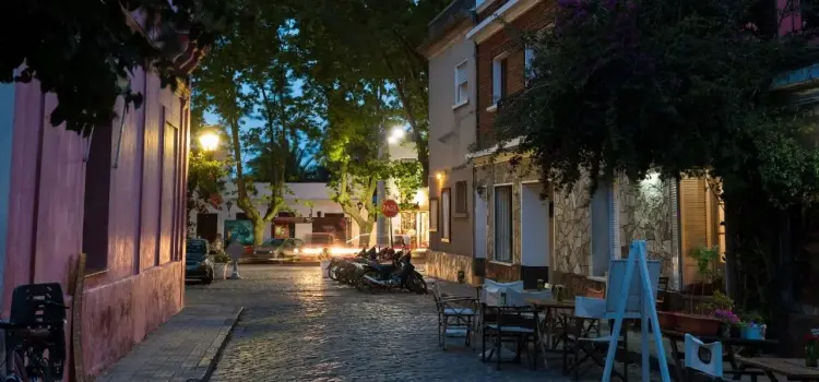Charming cobblestone street in historic Colonia del Sacramento at twilight with outdoor dining and colonial architecture