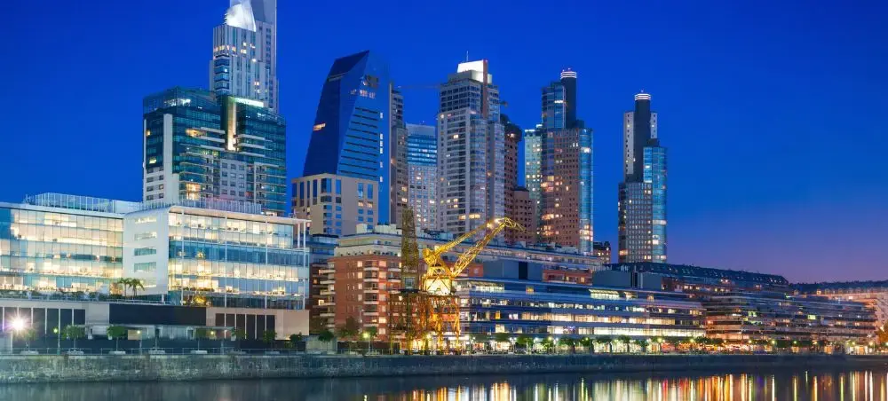 Modern waterfront skyline at dusk with illuminated skyscrapers reflecting in calm waters below