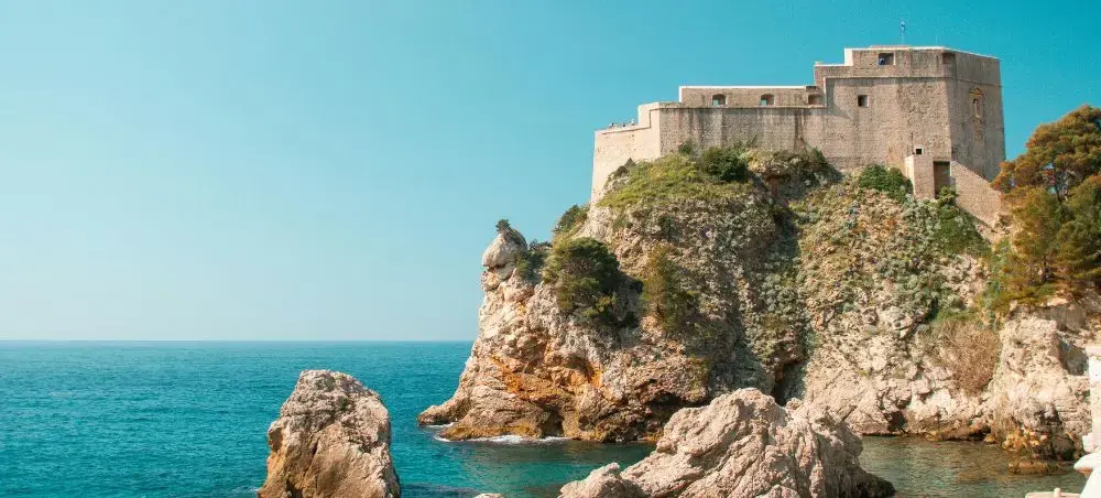 Medieval fortress perched on dramatic limestone cliffs overlooking turquoise Adriatic waters in Croatia
