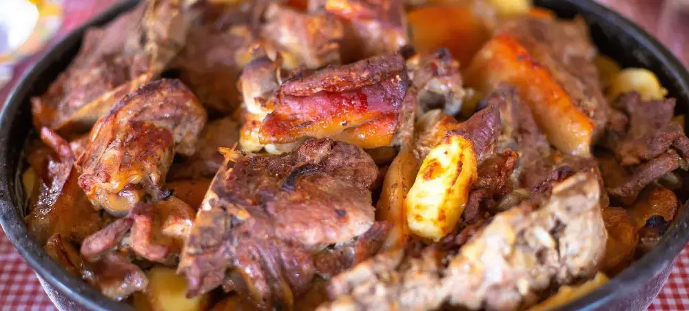 Traditional Croatian meat stew with sausages and vegetables simmering in cast iron pan