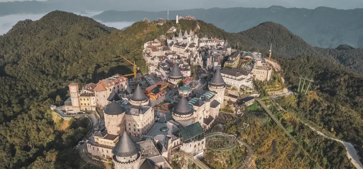 Aerial view of Ba Na Hills fantasy castle complex nestled in lush Vietnamese mountains near Da Nang