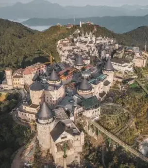 Aerial view of Ba Na Hills French village resort near Da Nang with medieval architecture and mountains