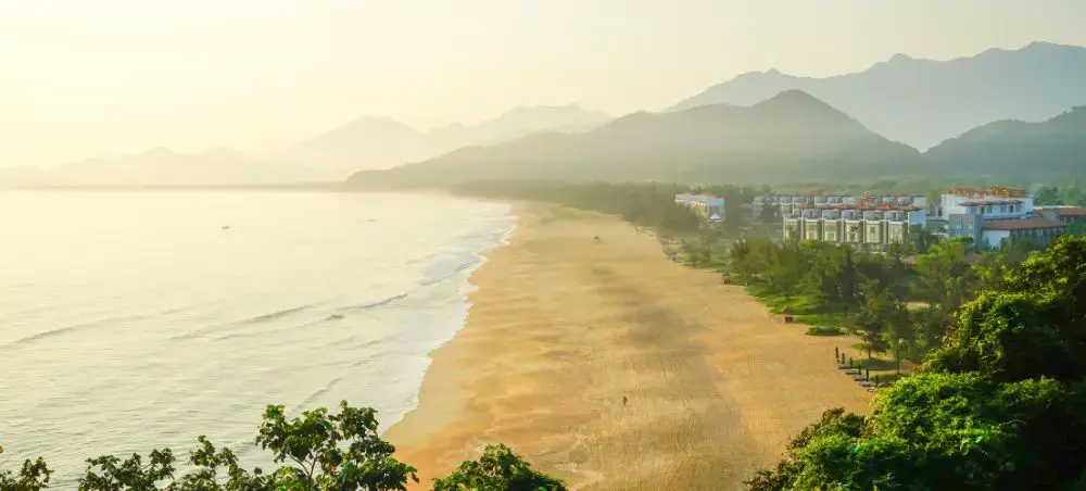 Golden sunset over Da Nang's pristine coastline with luxury resorts nestled between mountains and sea