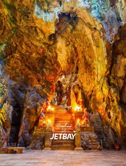 Illuminated limestone cave interior with golden rock formations and wooden walkway in Da Nang Vietnam