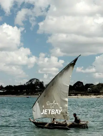 Traditional dhow sailboat with Jetbay branding cruising turquoise waters off Dar es Salaam coastline