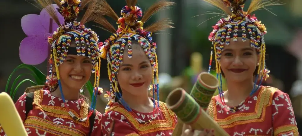 Three Filipino dancers in traditional beaded headdresses and embroidered costumes celebrate Davao City's cultural heritage