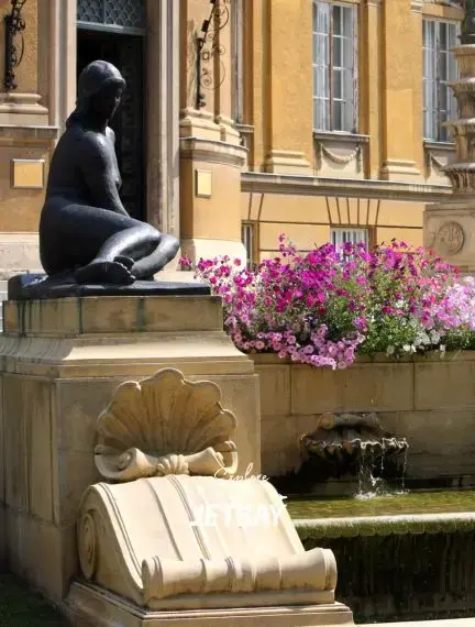 Bronze statue fountain with vibrant flowers at historic Debrecen landmark showcasing Hungarian cultural heritage