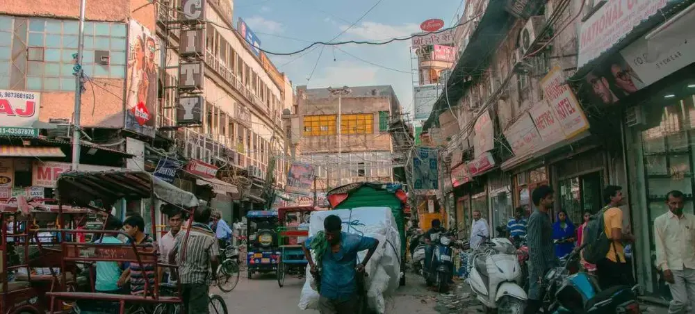 Bustling Delhi street market with colorful shops, vendors, and local traffic showcasing authentic Indian city life