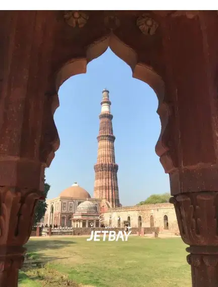 Qutub Minar tower viewed through ornate Mughal archway in Delhi, showcasing India's historic architecture