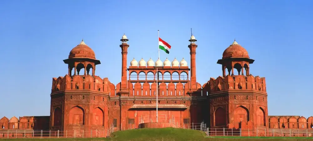 Red Fort's imposing Mughal architecture with Indian flag flying, showcasing Delhi's historic landmarks