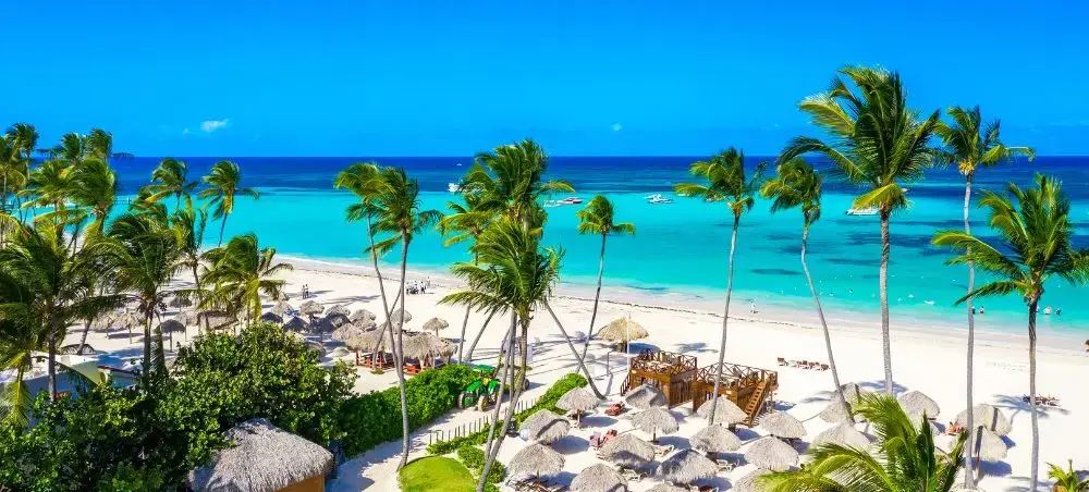 Pristine Dominican Republic beach with swaying palm trees, turquoise waters, and luxury resort amenities