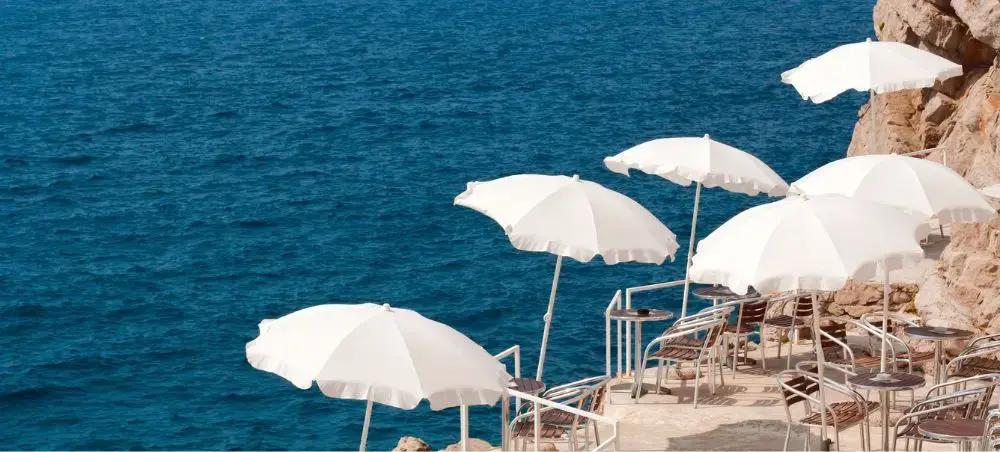 Elegant white umbrellas and seating overlooking crystal blue Adriatic waters in Dubrovnik, Croatia