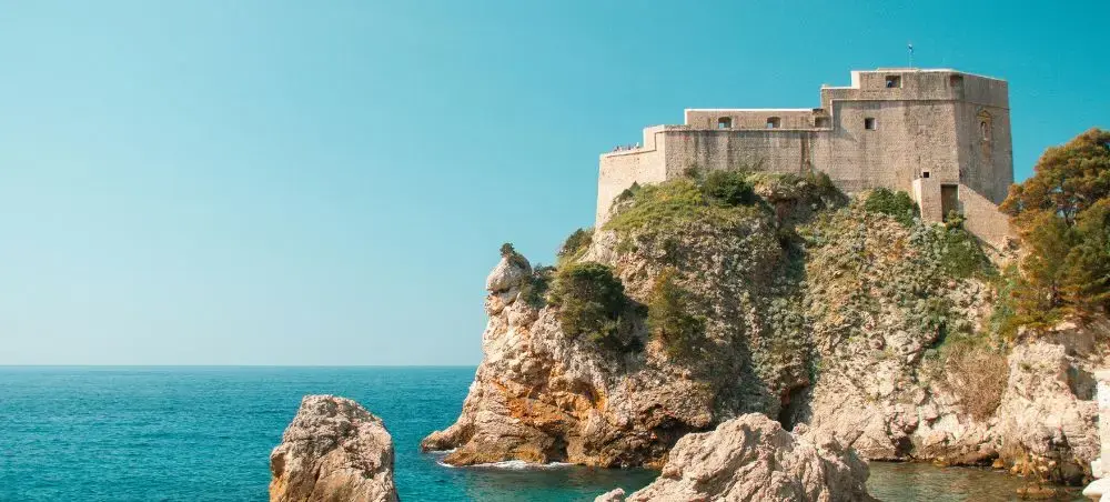 Medieval fortress walls of Dubrovnik perched dramatically on limestone cliffs above the sparkling Adriatic Sea