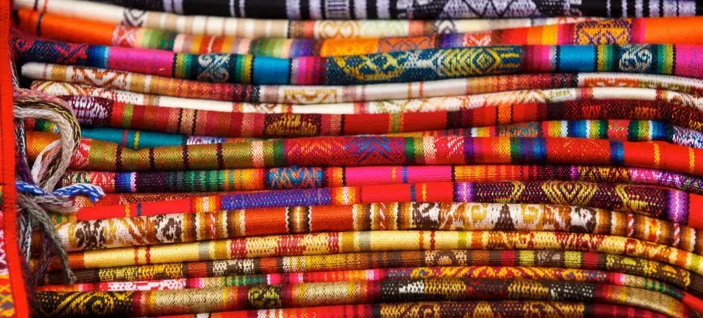Vibrant handwoven textiles stacked at Ecuador market showcasing traditional Andean craftsmanship and culture