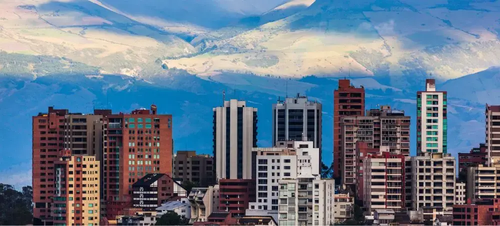 Modern high-rise buildings in Ecuador's capital city with snow-capped Andes mountains creating dramatic backdrop
