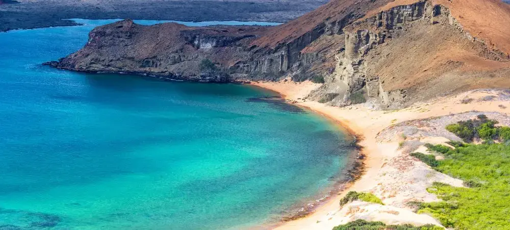 Pristine turquoise bay with golden sand beach surrounded by dramatic volcanic cliffs in Ecuador's coast
