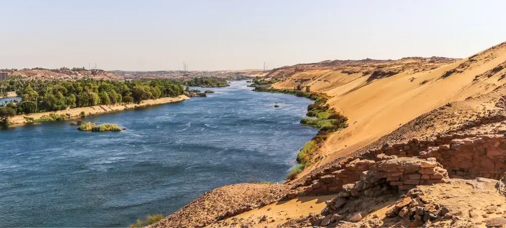 Nile River flowing through golden desert landscape with ancient ruins showcasing Egypt's timeless beauty