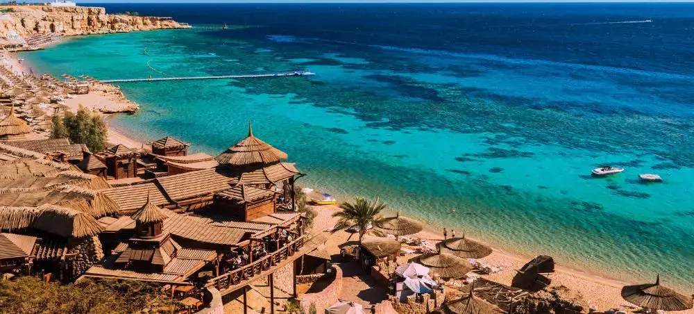 Pristine turquoise waters and luxury beach resort with traditional umbrellas along Egypt's Red Sea coast