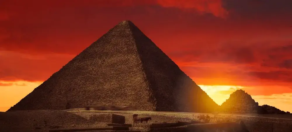 Ancient Egyptian pyramid silhouetted against dramatic sunset sky showcasing Egypt's iconic heritage