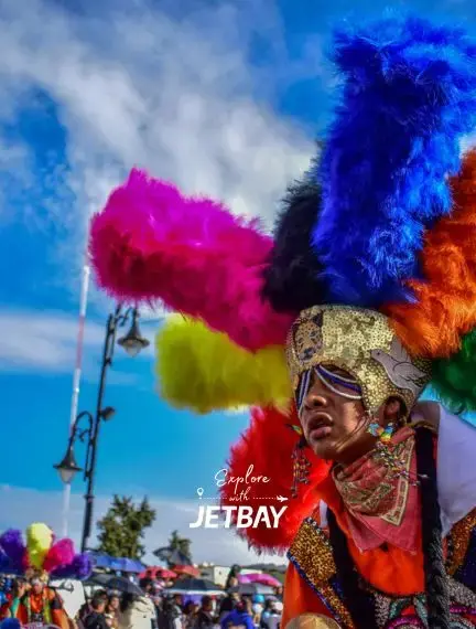 Vibrant carnival performer in elaborate feathered headdress celebrates at Encarnacion festival in Paraguay