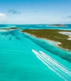 Luxury yacht cruising through crystal-clear turquoise waters near pristine Exuma islands in the Bahamas