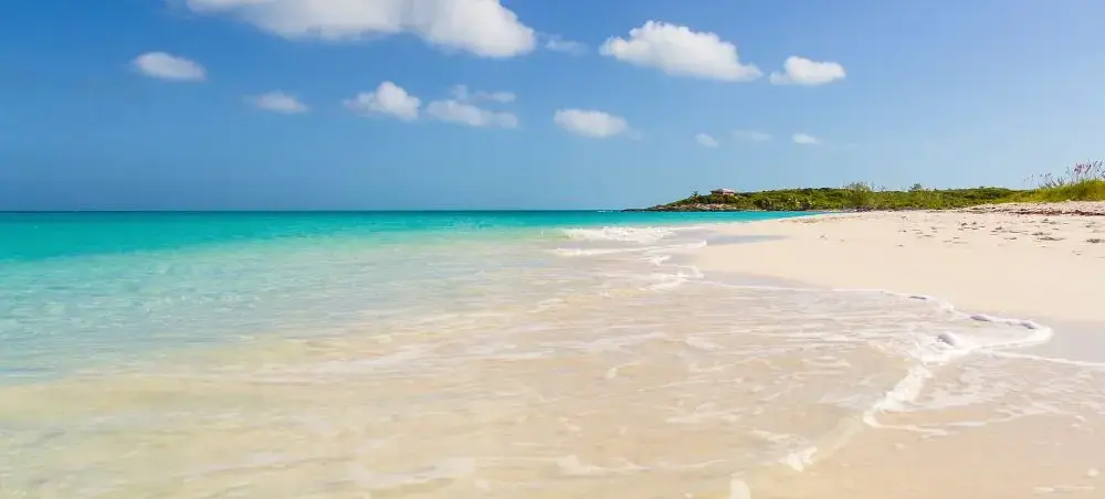 Pristine white sand beach with crystal-clear turquoise waters in Exuma, Bahamas under blue skies