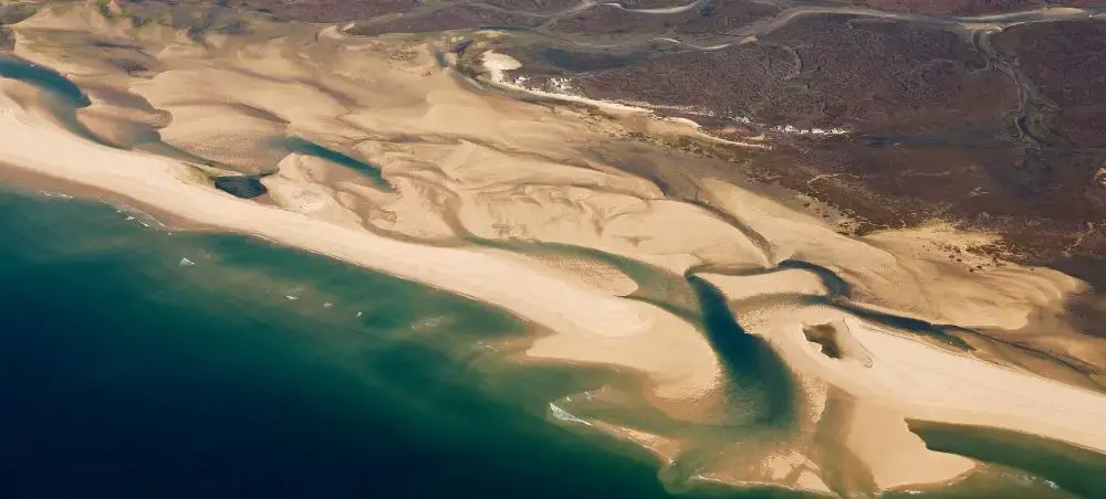 Aerial view of Faro's pristine coastline showing turquoise waters meeting golden sand dunes and lagoons