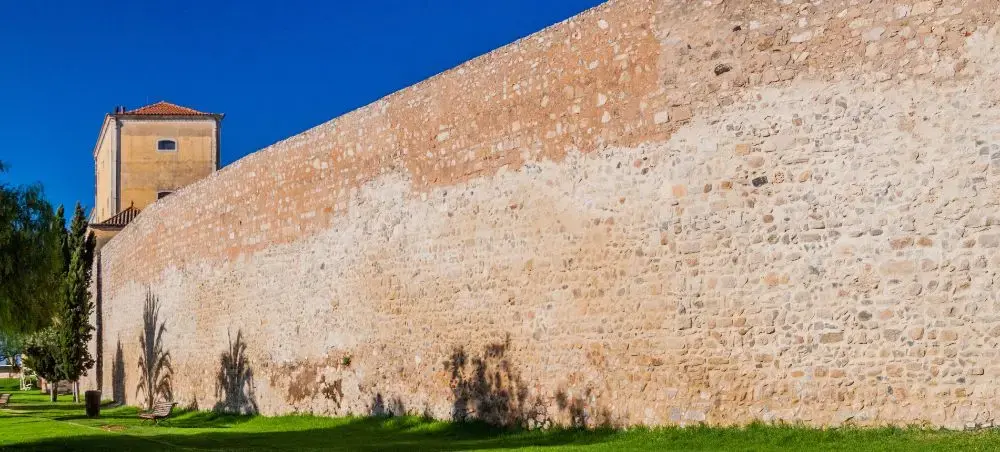 Ancient stone fortification wall in Faro showcasing Portugal's historic architecture under bright blue sky