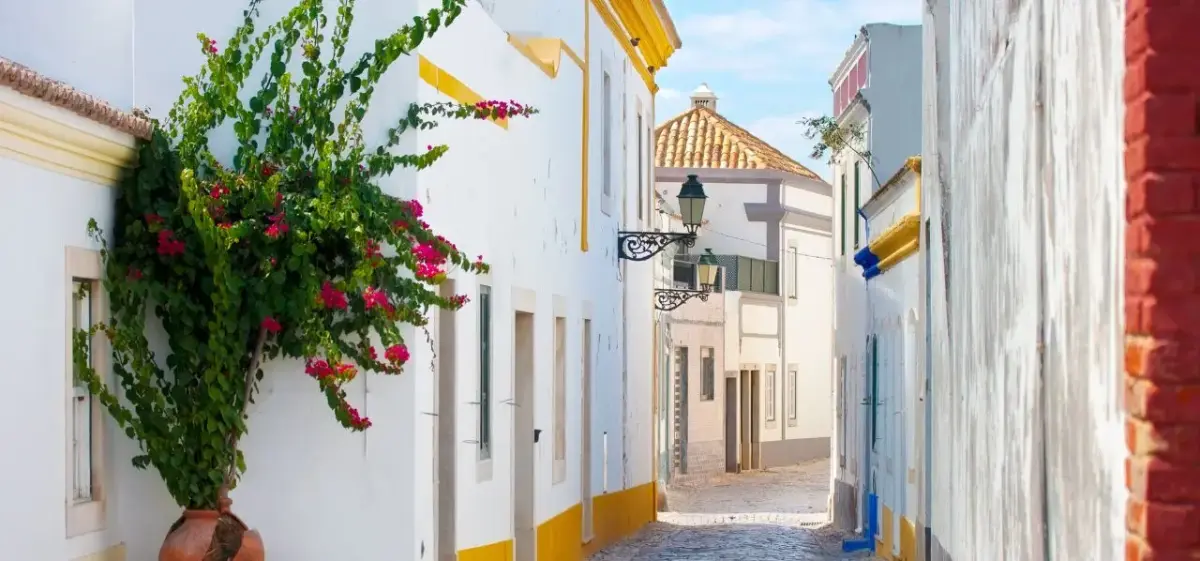 Charming cobblestone street in Faro's historic old town with whitewashed buildings and colorful bougainvillea