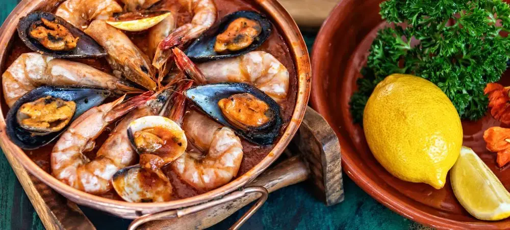 Traditional Portuguese seafood paella with prawns and mussels served in copper pan, showcasing Faro's cuisine