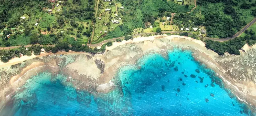 Aerial view of pristine Fiji beach with turquoise waters and coral reefs surrounded by lush tropical vegetation