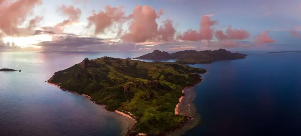 Aerial view of lush tropical islands surrounded by turquoise waters at sunset in Fiji's pristine archipelago