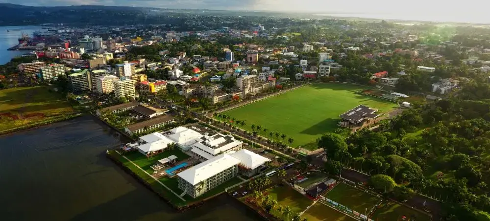 Aerial view of Suva, Fiji's capital city showcasing urban landscape, green spaces, and coastal setting