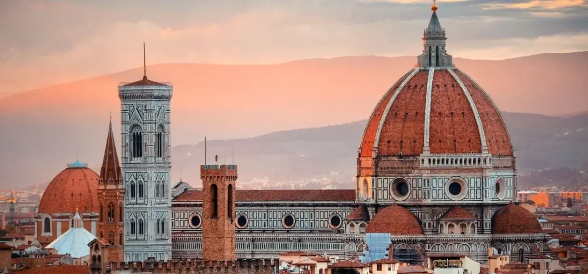 Florence Cathedral's iconic red dome dominates the Renaissance cityscape at golden hour sunset
