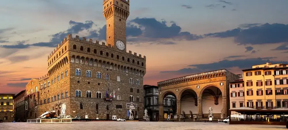 Palazzo Vecchio's medieval tower dominates Florence's Piazza della Signoria at golden hour, showcasing Italy's Renaissance heritage
