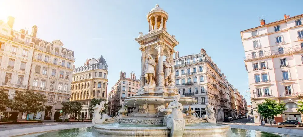 Historic fountain with ornate sculptures surrounded by elegant Haussmann-style buildings in Lyon, France
