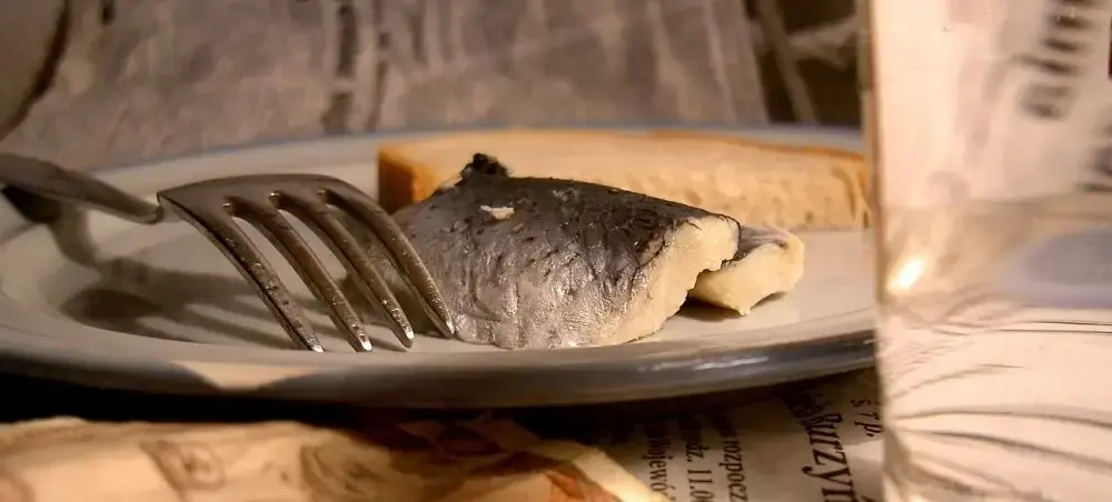 Fresh herring fillet with crispy skin served on elegant white plate, showcasing Gdansk's renowned Baltic seafood cuisine