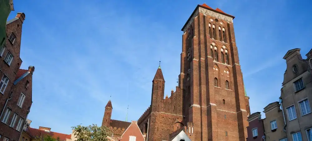 Historic red brick Gothic cathedral towers rising above colorful buildings in Gdansk's Old Town district