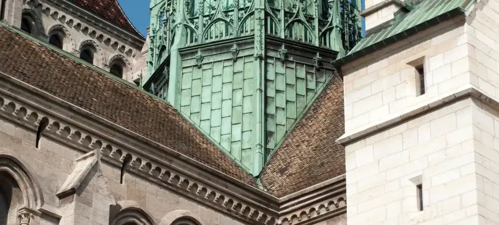 Historic Geneva cathedral with distinctive green copper spires and stone architecture in Switzerland