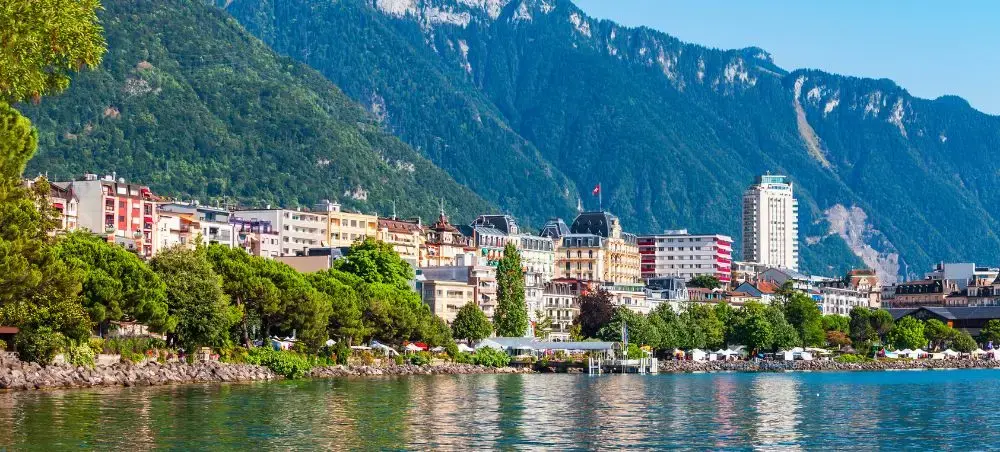 Scenic lakefront view of Geneva with colorful buildings, mountains, and pristine waters perfect for luxury travel