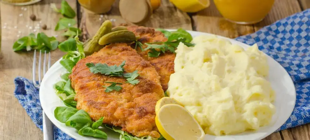 Golden schnitzel with creamy mashed potatoes and fresh greens showcasing authentic German cuisine