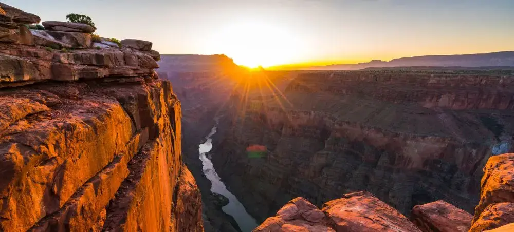 Dramatic sunrise over Grand Canyon's layered rock formations and Colorado River, showcasing America's iconic natural wonder