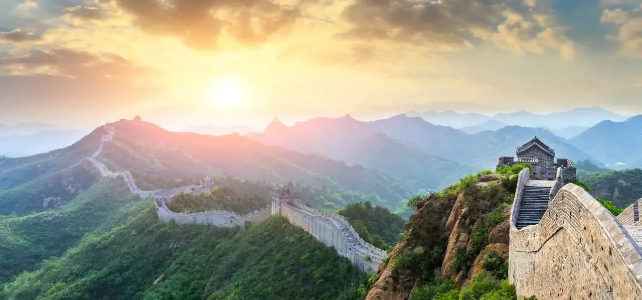 Great Wall of China winding through misty mountains at golden sunset, showcasing iconic travel destination