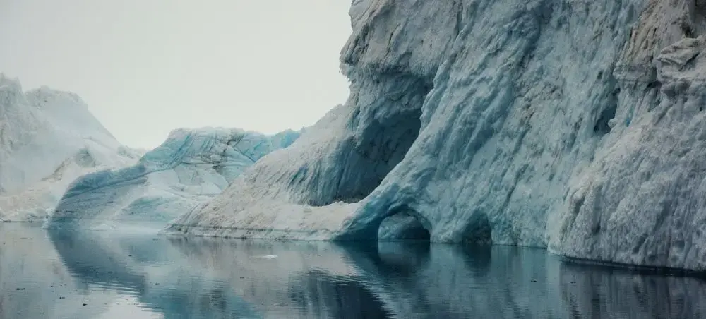 Towering icebergs reflected in calm Arctic waters showcase Greenland's pristine wilderness accessible by private jet