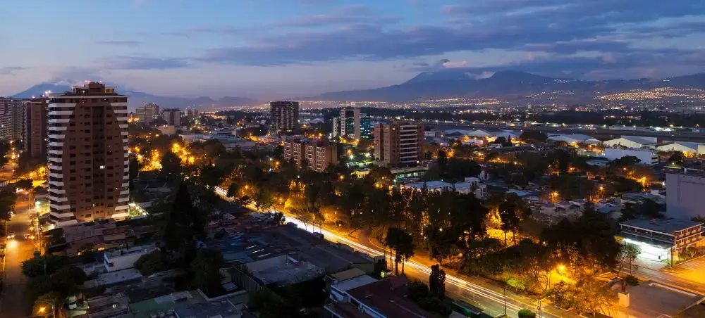 Guatemala City skyline illuminated at dusk with volcanic mountains in background showcasing Central America